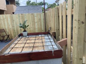 A wooden privacy fence under construction next to a concrete structure by Allende J. Service Corp in Miami, FL.