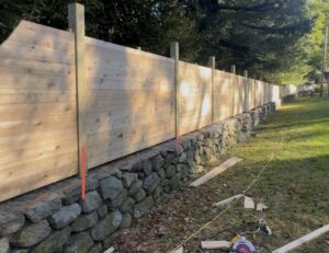 A wooden privacy fence under construction on a stone wall by RP Fencing & Gates in Brewster, NY