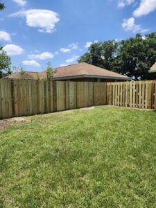 A newly installed wooden privacy fence extending around a corner in a residential backyard by Riggins Renovations LLC in Biloxi, MS.