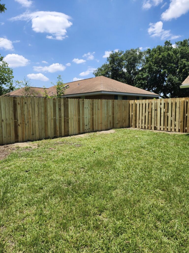A newly installed wooden privacy fence extending around a corner in a residential backyard by Riggins Renovations LLC in Biloxi, MS.