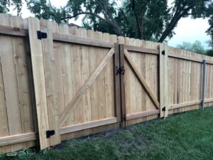 A newly installed wooden privacy fence featuring a wide double gate by Brothers Fence Co. in Madison, WI.