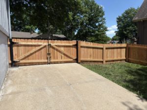 A newly installed wooden privacy fence with a double gate leading to a driveway by Fry's Fence LLC in Grain Valley, MO.