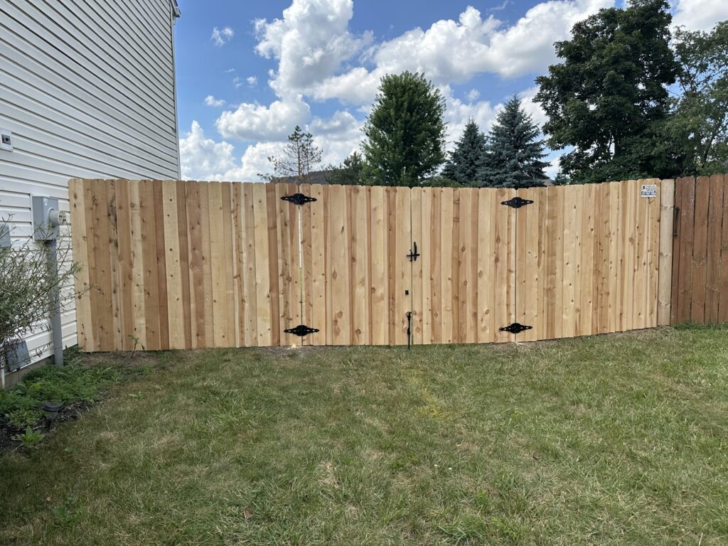 A wooden privacy fence with a double gate, expertly installed by Hoplite Services in Indianapolis, IN.
