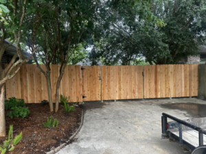 A newly installed wooden privacy fence featuring a double gate across a driveway by J&L Fence in Zolfo Springs, FL.