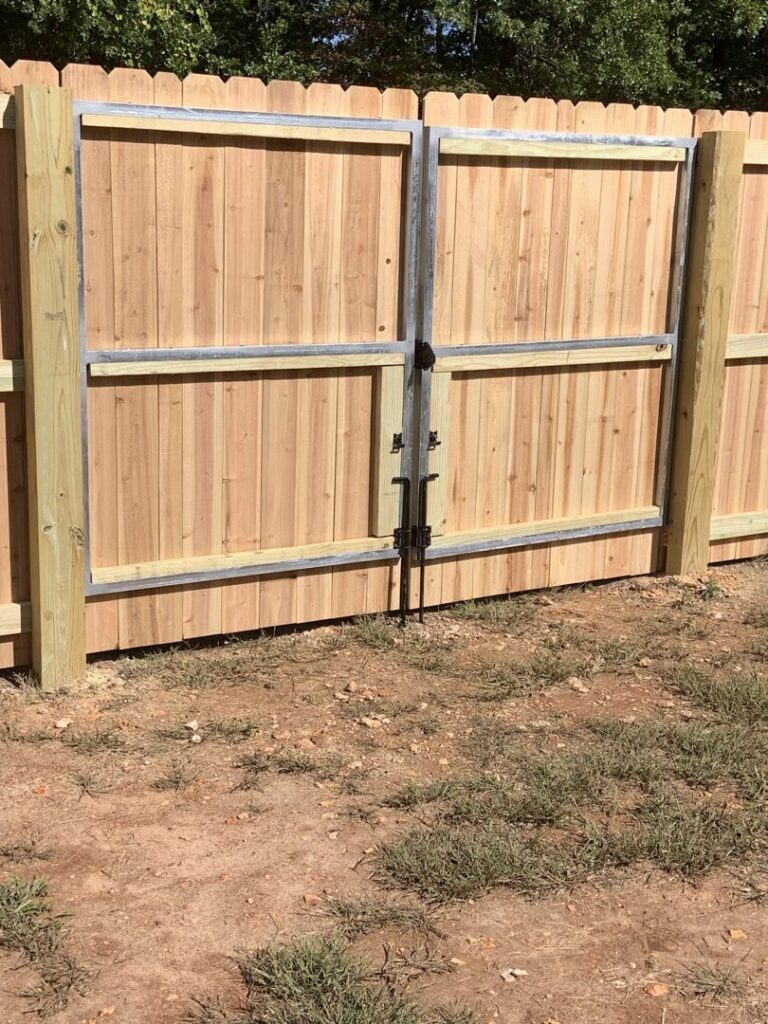 A sturdy wooden privacy fence featuring a double gate, installed by Superior Fence & Rail of Arkansas in Springdale, AR.