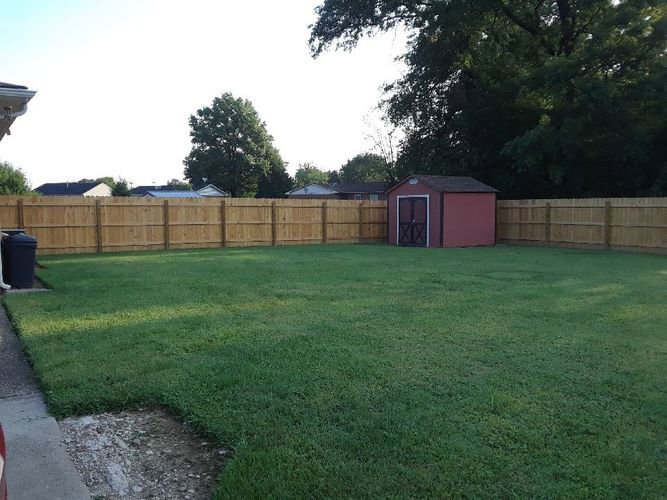 A wooden privacy fence installed along a driveway with landscaping by Best Fence & Gate LLC in Louisville, KY.
