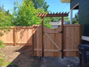 A wooden privacy fence with a matching gate and decorative arbor installed by Fix-A-Fence LLC in Portland, OR.