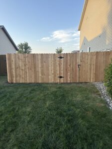A wooden privacy fence with a gate installed in a backyard by Aces Deck and Fence, LLC in Fargo, ND.