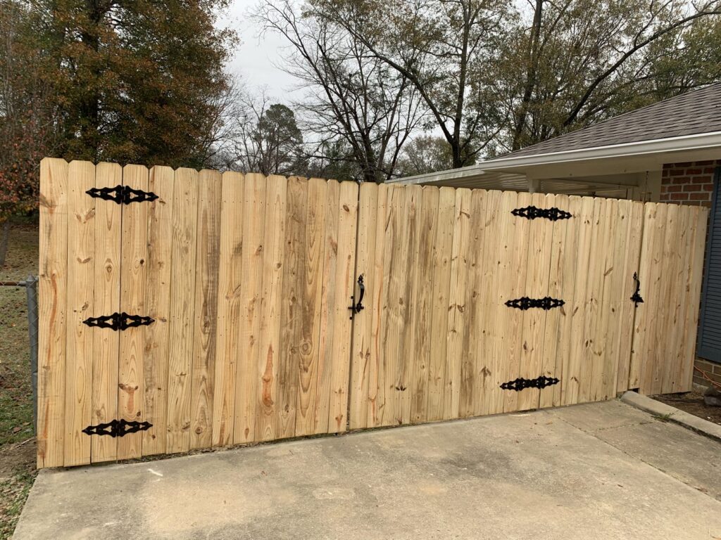 A wooden privacy fence with a gate featuring decorative black hinges and handles, installed by Pride Fence LLC in Overland Park, KS.