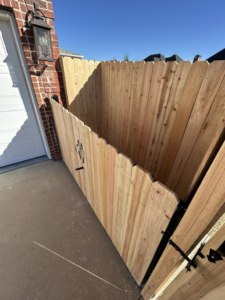 A custom wooden privacy fence gate installed next to a garage by Timber Wolf Fence Co. in Rogers, AR.