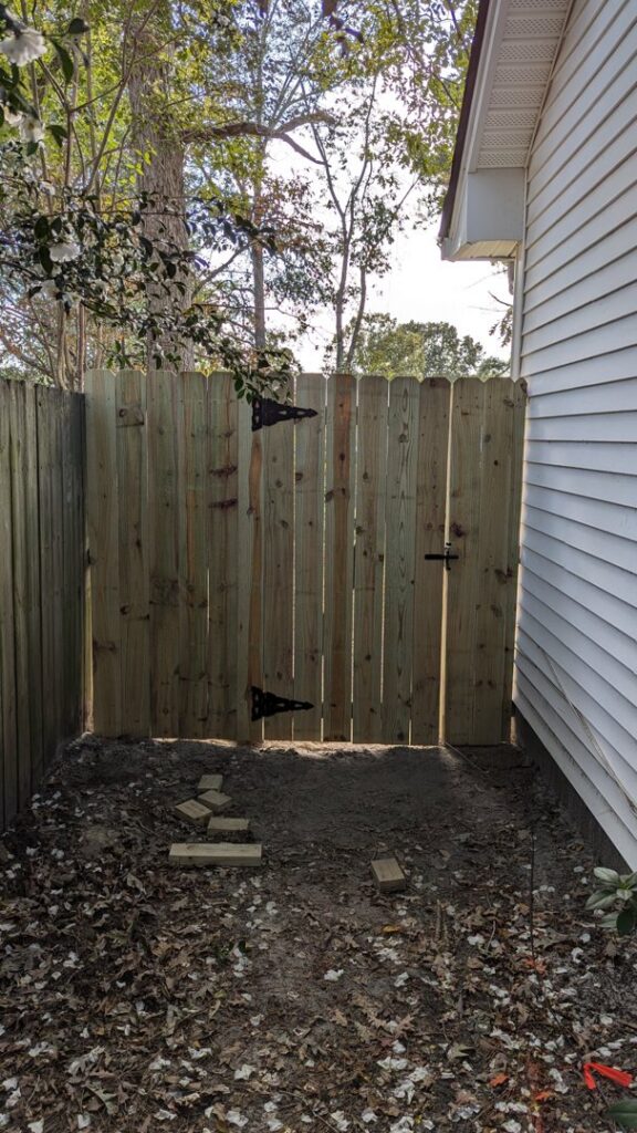 A wooden privacy fence with a gate installed in a side yard by Gifford Contracting & Repair - Custom Privacy Fencing in Goose Creek, SC.