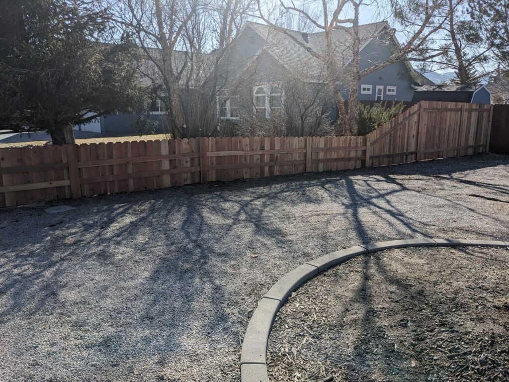 A well-built wooden privacy fence bordering a gravel driveway by Finest Fence in Simi Valley, CA.