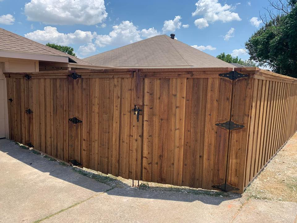 A newly installed wooden privacy fence with decorative black hardware in a residential backyard by BAR Z Fencing and Welding LLC in Midlothian, TX