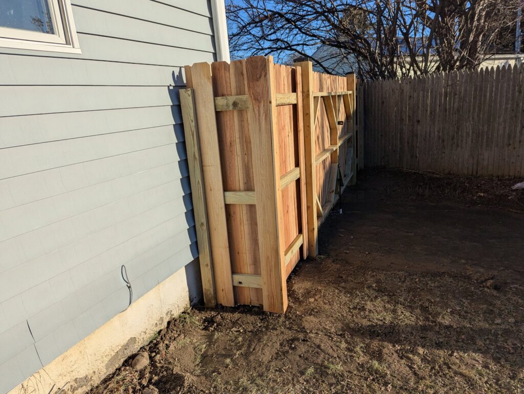 A wooden privacy fence being installed next to a house by Fence Pros Direct in Saunderstown, RI.
