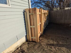 A wooden privacy fence being installed next to a house by Fence Pros Direct in Saunderstown, RI.