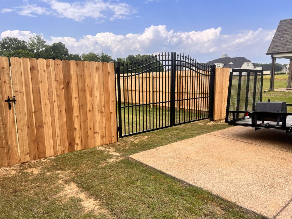 A new wooden privacy fence combined with an ornamental black iron gate by First Responder Outdoor Construction LLC in Bartlett, TN.