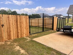 A new wooden privacy fence combined with an ornamental black iron gate by First Responder Outdoor Construction LLC in Bartlett, TN.