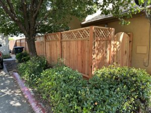 A residential wooden privacy fence with a lattice top and an integrated gate, expertly installed by Mega Fence in Thornton, CA.