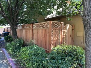 A wooden privacy fence with a decorative lattice top and an integrated gate, installed by Mega Fence in Thornton, CA.