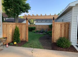 A newly installed wooden privacy fence with a decorative pergola-style gate entrance by Babb Custom Fence in Sioux Falls, SD.