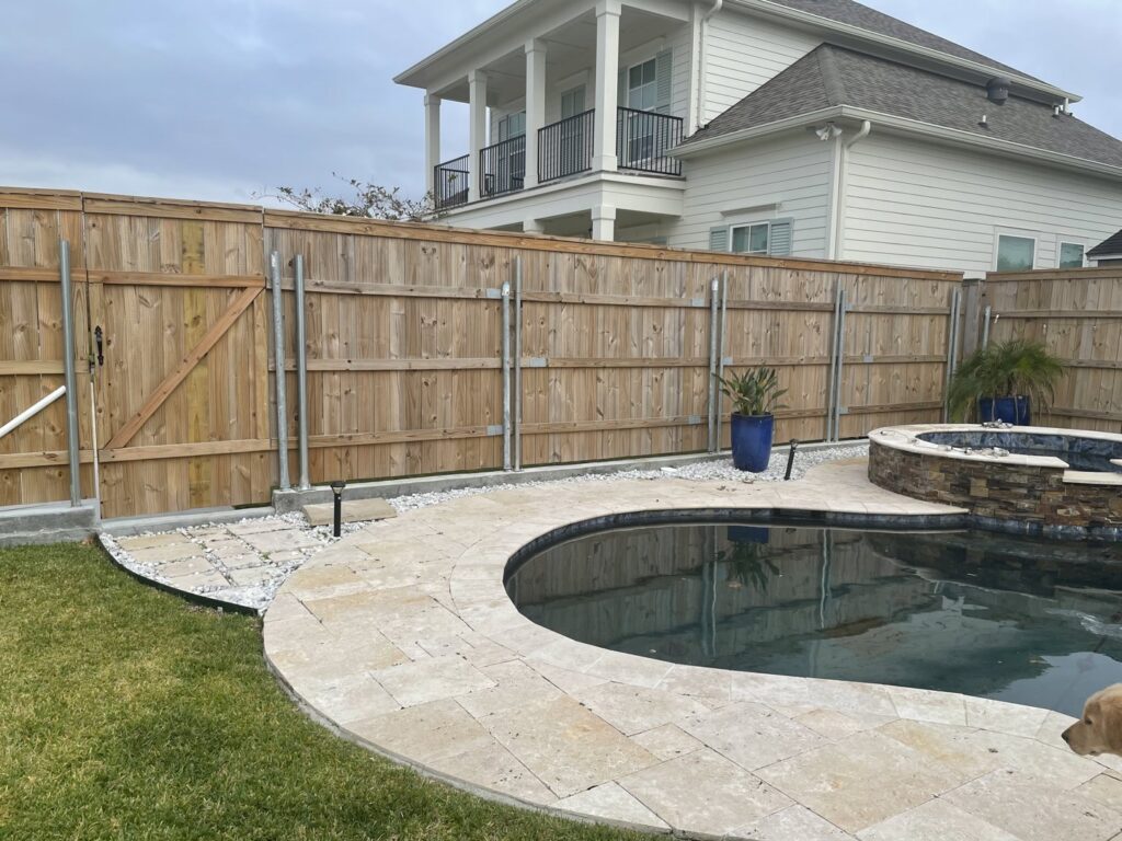A new wooden privacy fence with a gate installed around a swimming pool area by Amko Fence Co. in Kenner, LA.