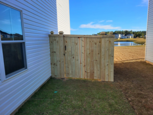 A section of new wooden privacy fence installed next to a house in a new construction area by Lundquist Home Improvements in Mount Pleasant, SC.