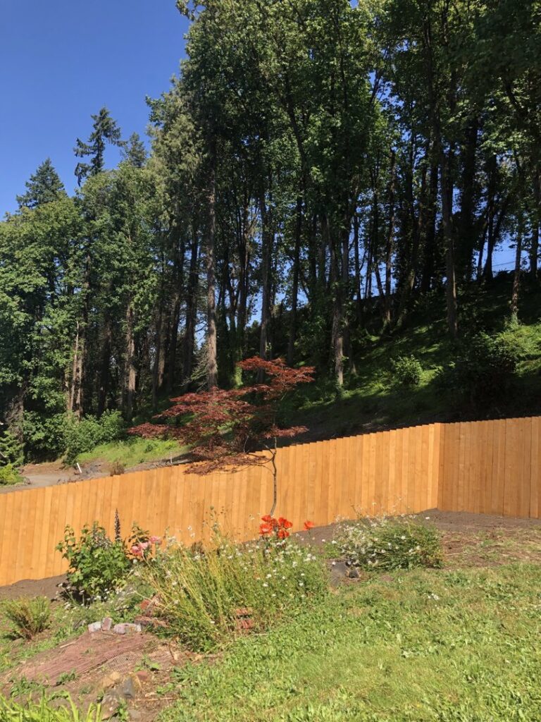 A newly installed wooden privacy fence on a sloped property by Pacific Woods Fence and Deck in Springfield, OR.