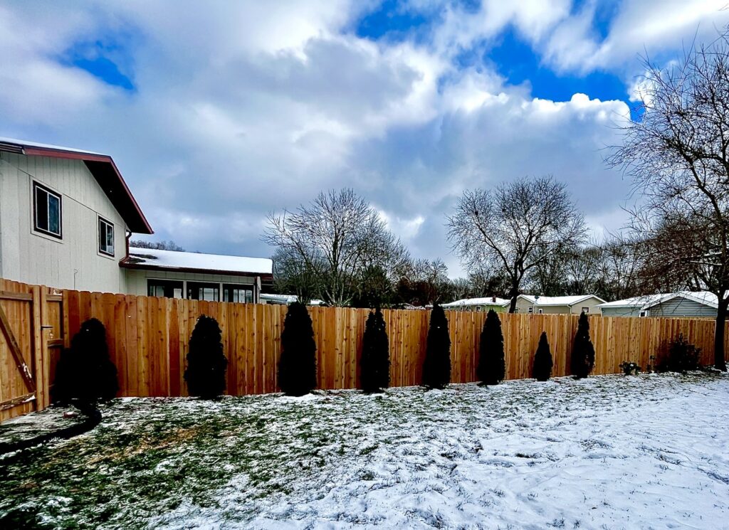 A tall wooden privacy fence standing strong in a snowy backyard by Brothers Fence Co. in Madison, WI.