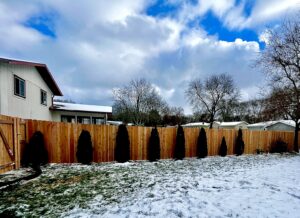 A tall wooden privacy fence standing strong in a snowy backyard by Brothers Fence Co. in Madison, WI.