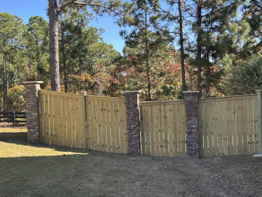 A wooden privacy fence with decorative stone pillars installed by JB Nealy Fence in Elgin, SC.