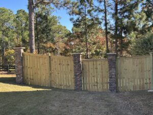A wooden privacy fence with decorative stone pillars installed by JB Nealy Fence in Elgin, SC.