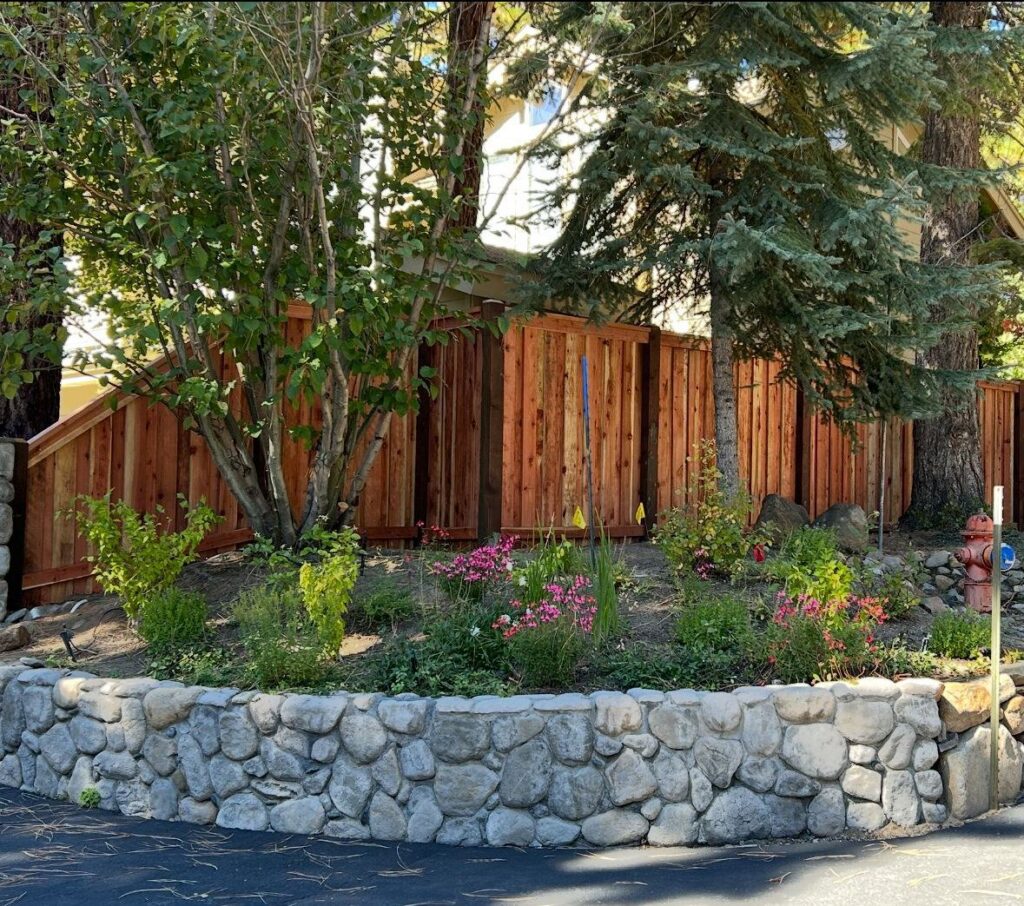 A custom wooden privacy fence installed behind a decorative stone retaining wall by Finest Fence in Simi Valley, CA.