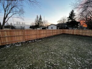 A newly installed wooden privacy fence in a backyard during sunset by Brothers Fence Co. in Madison, WI.