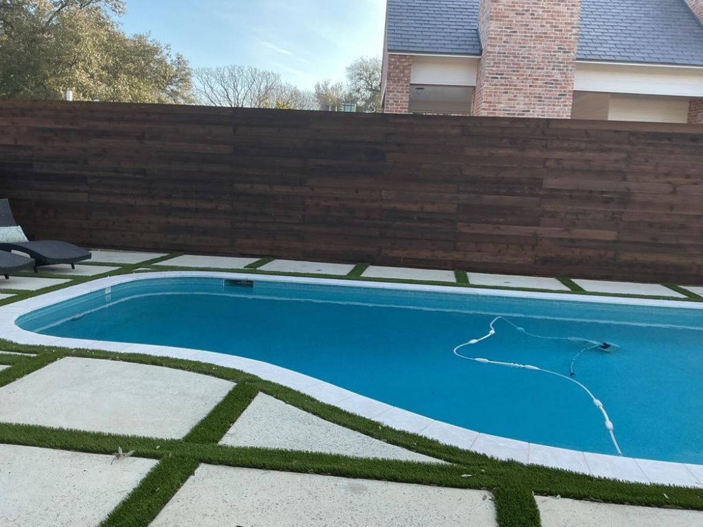 A modern wooden privacy fence installed behind a swimming pool by B & S Fence Company in Haltom City, TX