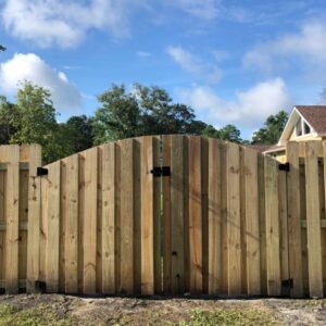 A completed wooden privacy fence with an elegant arched gate installed by Heavenly Gates Construction LLC in Miami, FL