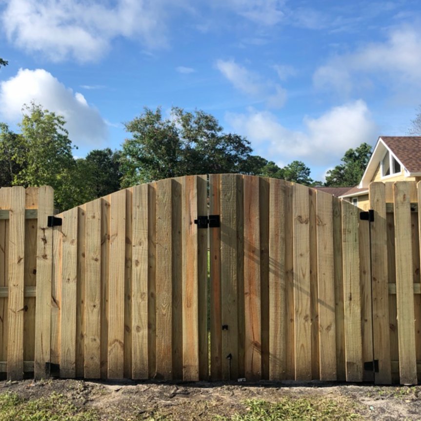 A completed wooden privacy fence with an elegant arched gate installed by Heavenly Gates Construction LLC in Miami, FL