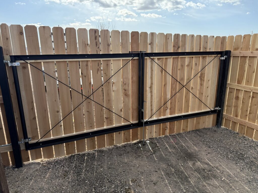 A wooden privacy fence with a black metal gate installed by Pueblo Fence Co in Pueblo West, CO.