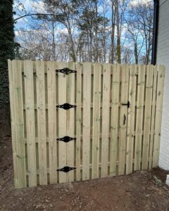 A wooden privacy fence with decorative black hinges and a latch installed by Georgia Select Fence in Senoia, GA.