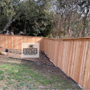 A newly installed wooden privacy fence with a decorative top trim by Tropical Fencing And Wood Works in Page, TX.