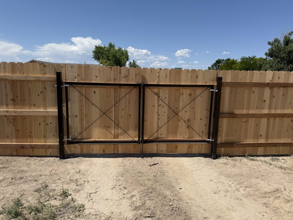 A wooden privacy fence with a double black gate installed by Pueblo Fence Co in Pueblo West, CO.
