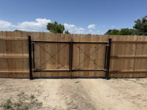 A wooden privacy fence with a double black gate installed by Pueblo Fence Co in Pueblo West, CO.