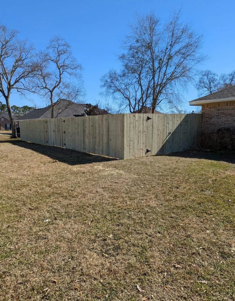 A newly installed wooden privacy fence featuring two gates in a residential area by Riggins Renovations LLC in Biloxi, MS.