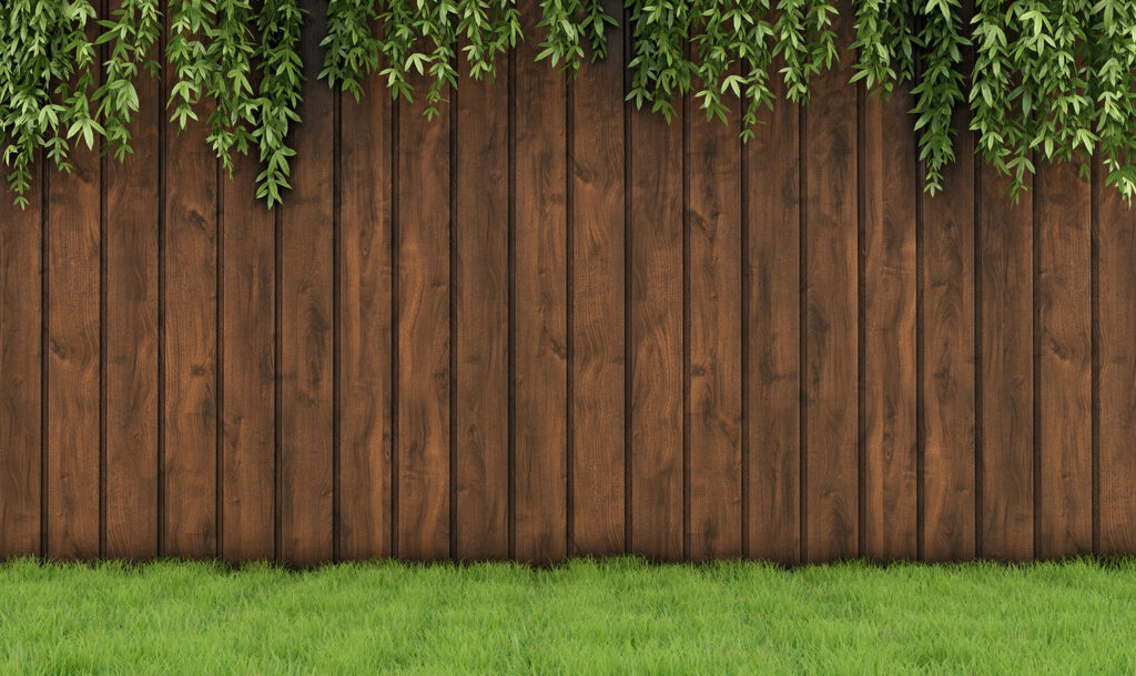 A sturdy wooden privacy fence with green foliage hanging over, installed by Fence Company Chicago in Chicago, IL