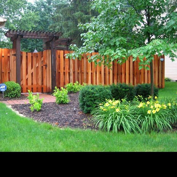 A beautiful wooden privacy fence with an integrated gate and pergola installed by McDaniels Fencing in Huntington, WV.