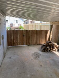 A custom wooden privacy fence with a gate installed under a patio area by Petty Fence Company LLC in Evansville, IN.