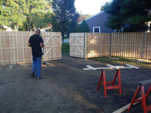 A newly installed wooden privacy fence with double gates, showcasing a project by Ocean State Fence Works LLC in North Kingstown, RI.