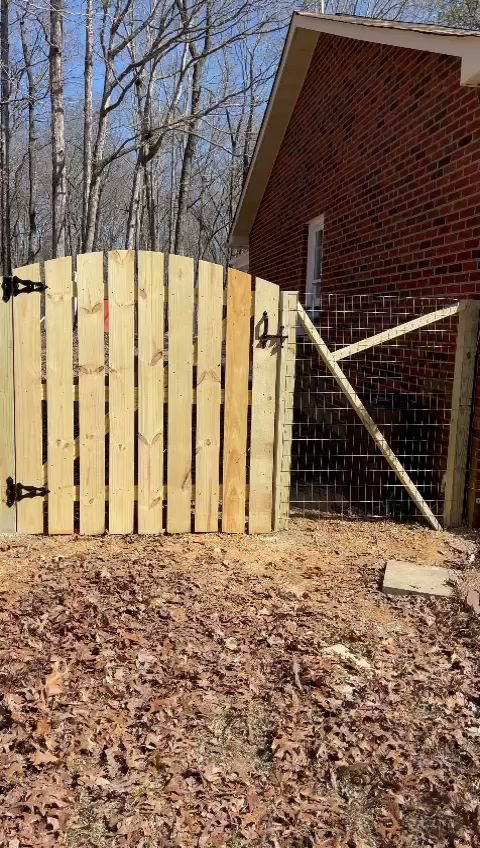A wooden privacy gate installed next to a wire mesh fence by Sunrise Fences in Monroe, NC.