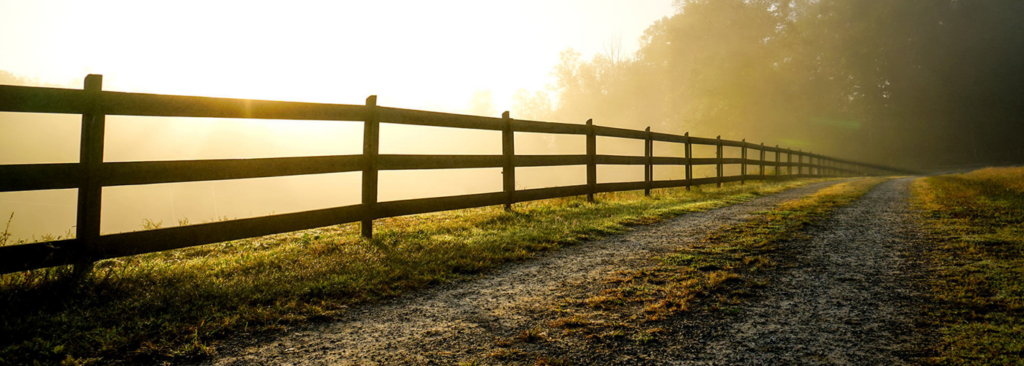 A beautiful wooden rail fence installation by Lawrence Fence Company in Lawrence, KS, stretching along a path.