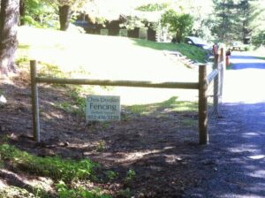 A wooden rail fence with wire mesh and a business sign for Chris Doolan Fencing, installed by Doolan Fence in Montpelier, VT.