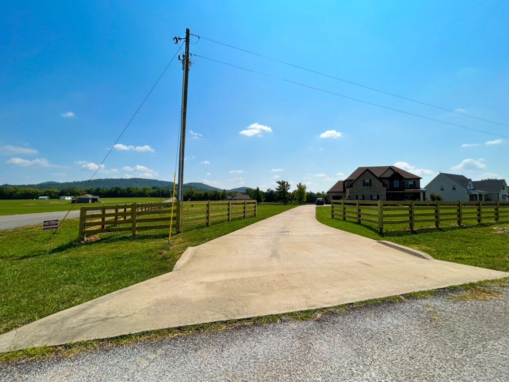 A long wooden split-rail fence with wire mesh installed along a residential driveway by Pro Fence in Decatur, AL
